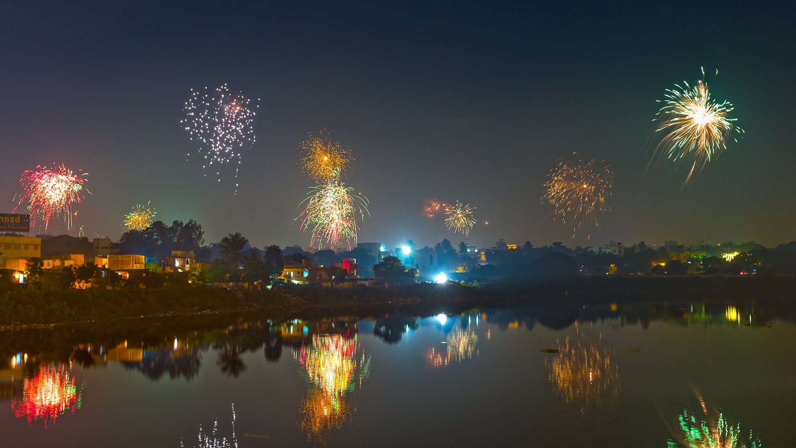 Fireworks light up the night sky over Chennai, reflected in still water, during Deepavali in Tamil Nadu